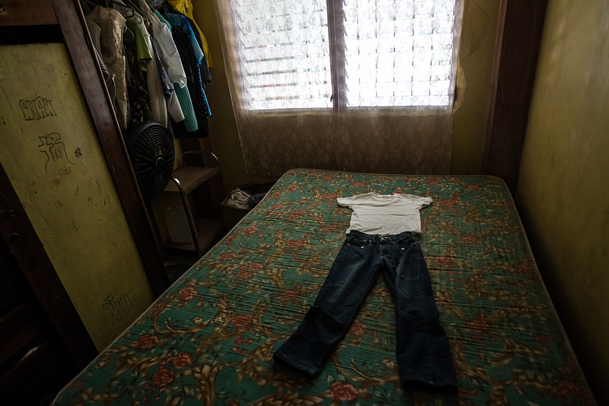 Family members show the clothes, laid on the bed of late seven-year-old Kenneth Alejandro Castellano Raudales, who was found tortured and murdered by the Mara-18 gang, according to local police. In the same week, the gang killed Kenneth’s 12-year-old brother, Anthony Castellano. The family lives in the La Pradera neighborhood, a Mara-18 gang stronghold in San Pedro Sula, Honduras. The police report that seven children were murdered by Mara-18 gang members in this neighborhood in May 2014. Photo by Meridith Kohut.
